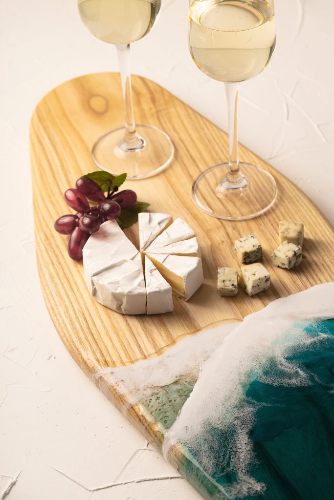 Glasses with wine and cheese on a board with imitation of sea waves